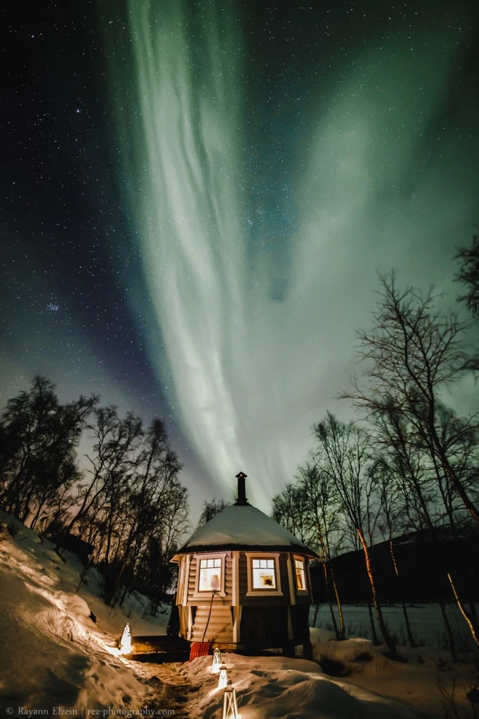 Lit gazebo under the northern lights in Finnish Lapland
