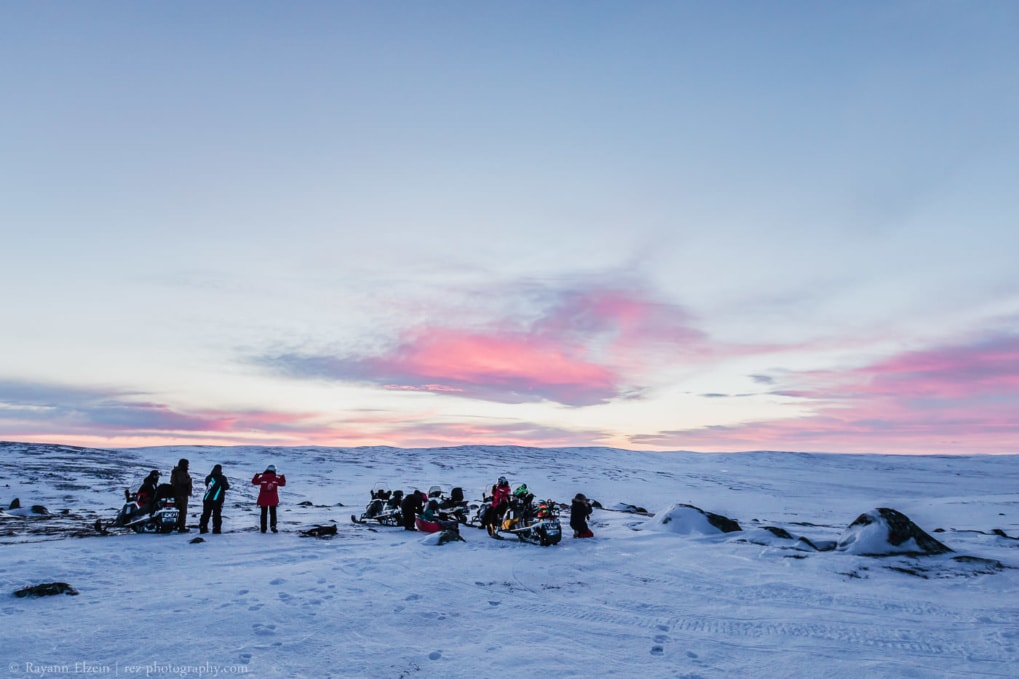 Group of photographers and snowmobiles on the fells near Nuorgam, with very pink clouds in the background