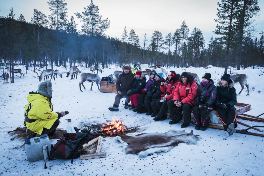 Group of photographers sitting and listening to the reindeer herder's stories in Finnish Lapland