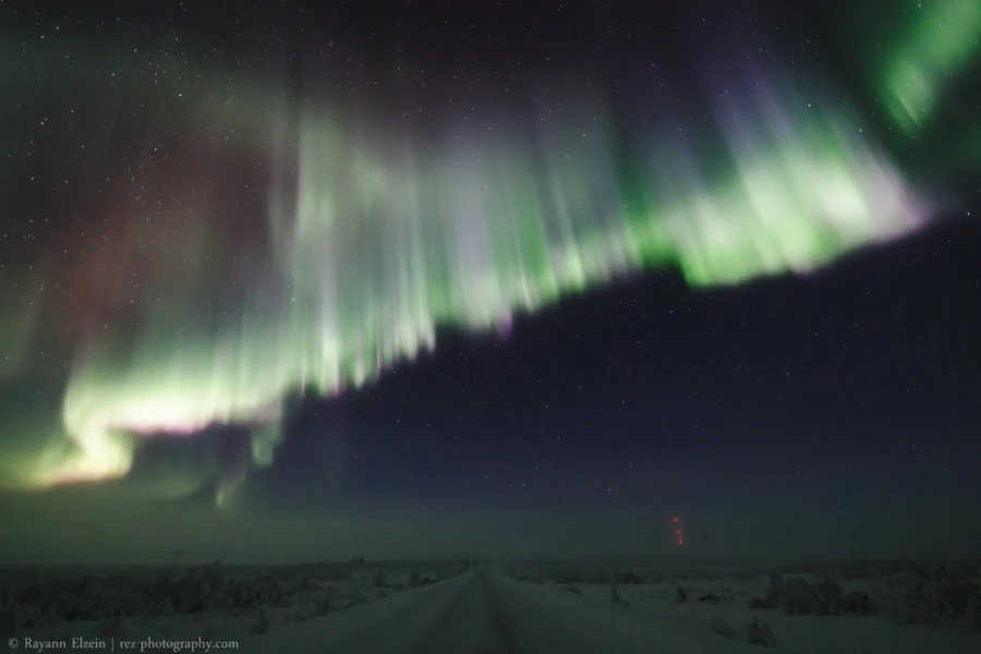 Strong northern lights above the road in Finnish Lapland